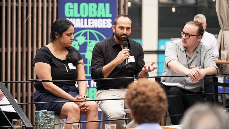 Three panelists on a rooftop stage in New York under a Global Challenges banner, seen past the soft heads of the audience.